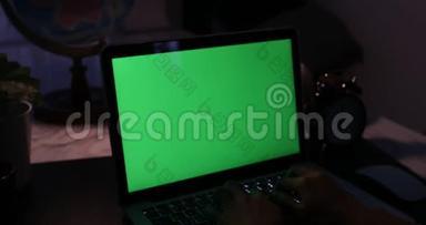 带有绿色屏幕的笔记本电脑。 黑暗的办公室。 多利加入。 完美地放置你自己的图像或视频。 正在使用的技术绿色屏幕。 C.C